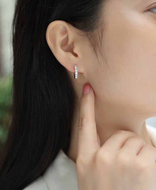 Close-up of a person wearing a diamond earring with a blurred background