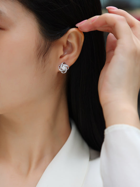 Close-up of a person wearing a floral earring with a hand adjusting it.