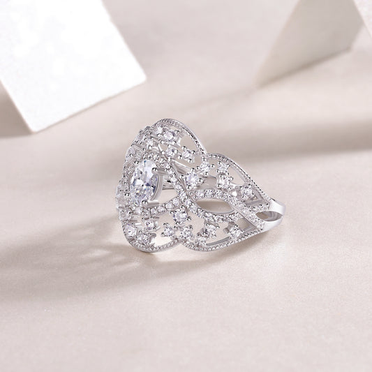 Silver ring with intricate design on a light pink background