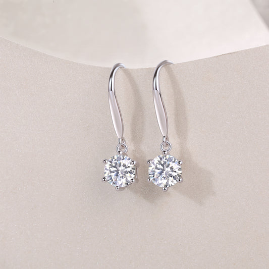 Silver earrings with clear gemstones on a beige background